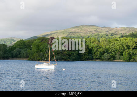 Un petit bateau à voile blanc, flotte sur l'eau, Coniston Lake District, Royaume-Uni. Banque D'Images