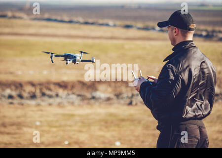 Young man holding remote controller dans ses mains et de prendre des photos aériennes avec petit drone compact. Focus sélectif. Banque D'Images