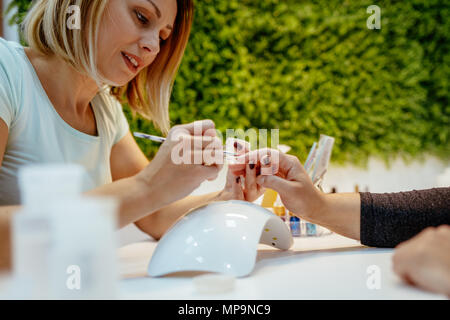 Heureux les ongles peinture coiffeur des clientes au salon de beauté. Banque D'Images