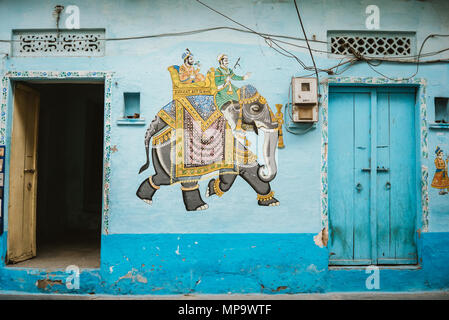 Une peinture colorée d'un éléphant sur un mur bleu sarcelle dans entre les embrasures à Udaipur, Inde Banque D'Images