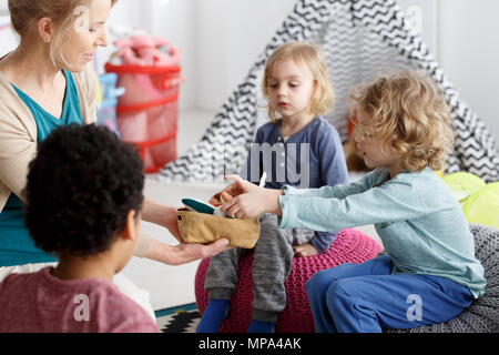 Les petits enfants et leur enseignant le nettoyage des jouets après jouer Banque D'Images