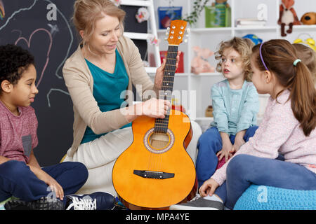 Enseignant de maternelle montrant aux enfants comment jouer de la guitare Banque D'Images