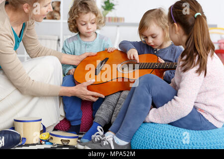 Enseignant de maternelle aider les petits enfants à jouer de la guitare Banque D'Images