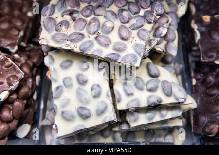 Gros plan macro de tas de morceaux de chocolat blanc, de nombreux bars avec morceaux d'arachides, amandes sur le bac s'affichent dans confiserie chocolatier shop Banque D'Images