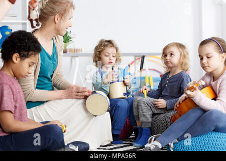 Quatre enfants d'avoir du plaisir dans le jardin d'enfants jouant les instruments Banque D'Images