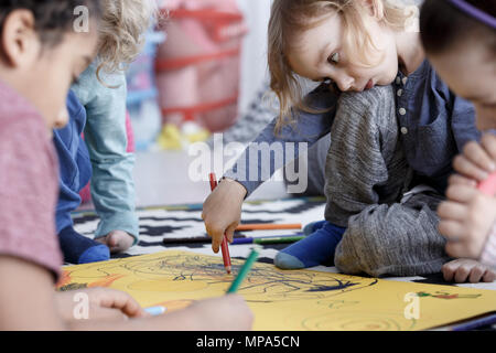 Petite fille dessinant la photo dans un groupe d'âge préscolaire à la maternelle Banque D'Images