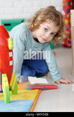 Happy little boy playing with colorful fusée sur un tapis Banque D'Images