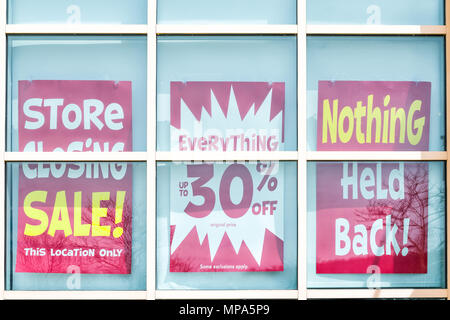 Gros plan du jaune et rouge bannière fermeture de magasin enseigne-affiche sur la fenêtre de verre de l'édifice du magasin pour se retirer des affaires de faillite Banque D'Images