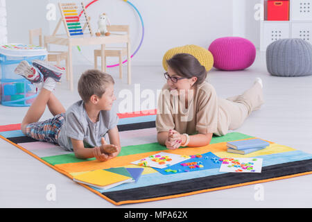 Tourné d'une jeune femme et un petit garçon allongé sur un tapis et d'étudier ensemble Banque D'Images