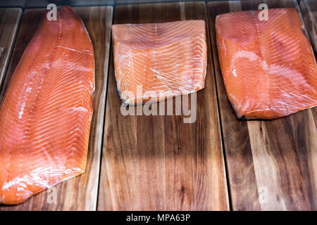 Grand filet de saumon cru fumé coupé sur le stand de fruits de mer shop store sur l'écran enveloppé dans du plastique Banque D'Images