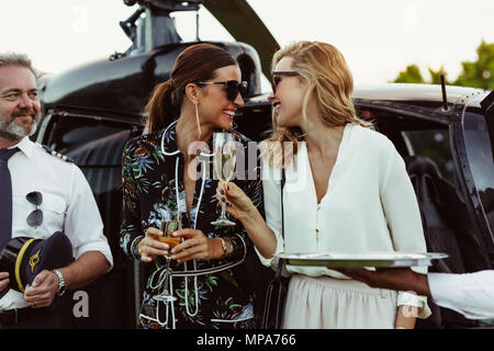 Les joyeux amis, pour avoir un hélicoptère à l'extérieur du vin avec pilot standing by. Aux femmes de bénéficier d'un verre de bienvenue à bord d'un hélicoptère. Banque D'Images