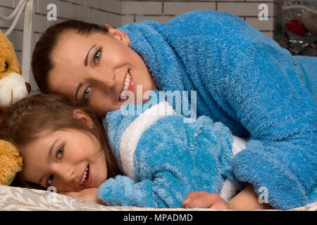 Maman et sa fille dans la même robe terry bleu étendu sur le lit Banque D'Images