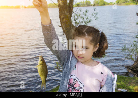 Girl holding un poisson pris dans sa main, se réjouir et smiling Banque D'Images