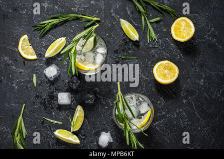 Verre à cocktail gin tonic avec du citron, du romarin et de la glace sur une table en pierre. Vue d'en haut Banque D'Images