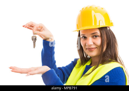 Jeune femme séduisante ingénieur ou architecte présentant des clés de la maison et souriant comme concept immobilier isolé sur fond blanc Banque D'Images