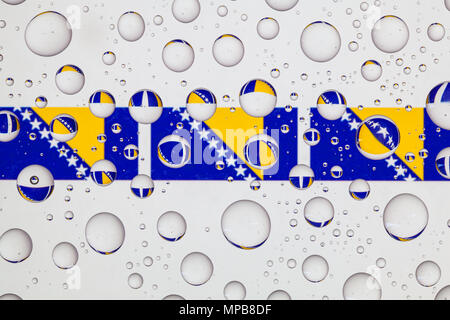 Drapeaux de la Bosnie-Herzégovine derrière un verre recouvert de gouttes de pluie. Banque D'Images