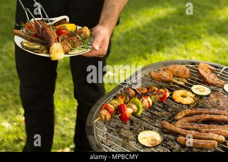 Close-up of man holding assiette pleine de nourriture grillée Banque D'Images