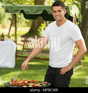 Young handsome man grilling dans le jardin Banque D'Images