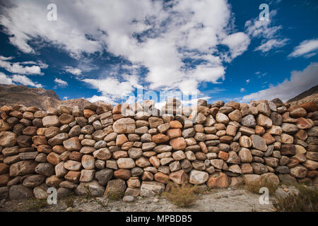 Le mur de pierre construit à partir des différentes tailles des blocs en gris, brun fauve, teintes. Ciel bleu avec des nuages blancs. Idéal pour les illustrations et les collages. Banque D'Images