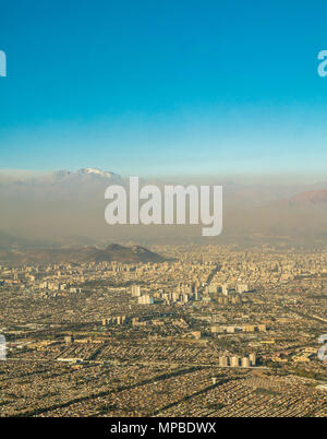 Vue sur Santiago, Chili prises à partir de la fenêtre de l'avion à Cerro San Cristobal et Andes couvertes de neige au-dessus de pics couche de smog et de la pollution atmosphérique Banque D'Images