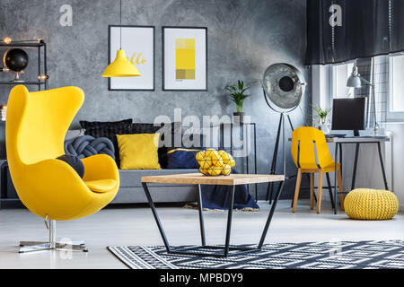 Hipster avec table basse, fauteuil design jaune et des murs en béton Banque D'Images