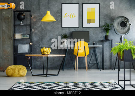 Cette chambre élégante avec mur texturé gris, bureau, des affiches et de l'ordinateur Banque D'Images