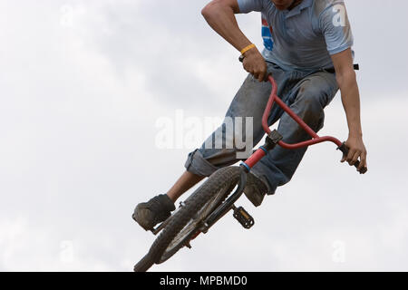 Un vélo BMX (Moto-cross(X)) dans l'air contre un ciel nuageux Banque D'Images