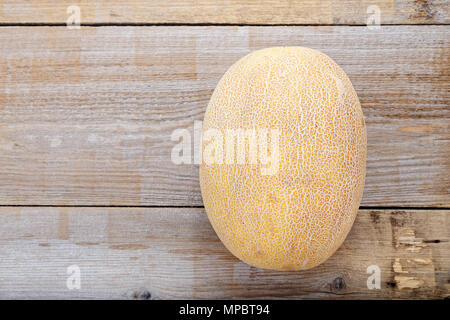 Tout un melon mûr sur une table marron foncé Banque D'Images