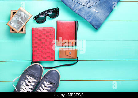 Set de voyage, Passeport, e-book, chaussures, lunettes de soleil, appareil photo. on a wooden surface turquoise, une vue de dessus Banque D'Images