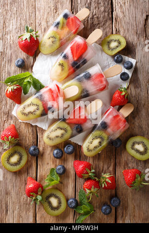 Les popsicles fraîchement préparés avec des produits frais de glace fraises, kiwis et les bleuets sur un bâton sur une table. Haut Vertical Vue de dessus Banque D'Images