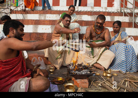 L'Inde, Uttar Pradesh, Varanasi, un pundit effectue une puja pour la famille d'un défunt à Kedar Ghat. Banque D'Images