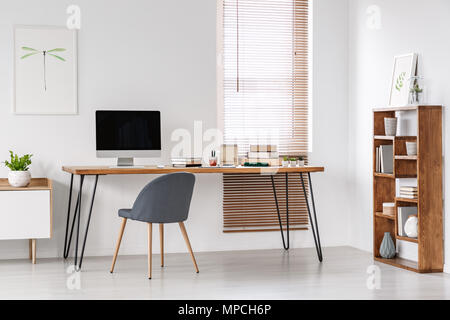 Chaise gris à 24 avec le moniteur de l'ordinateur dans l'espace minimal à l'intérieur de l'affiche. Photo réelle Banque D'Images