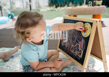 Un enfant en s'appuyant sur un tableau noir et apprendre à lire l'heure. Un portrait d'un petit garçon le temps d'apprentissage à la maison. Banque D'Images