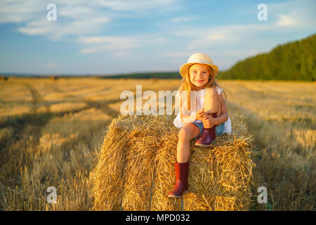 Petite fille dans un champ avec des rouleaux de foin Banque D'Images