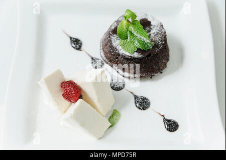 Le Dessert. Fondan chocolat et crème glacée à la vanille. Décorées avec des feuilles de menthe et de framboises. Banque D'Images