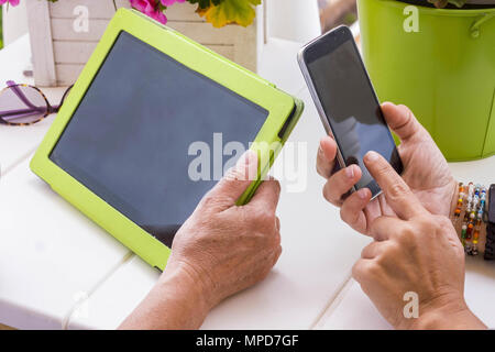 Deux adultes femme différents âges comme la mère et l'utilisation de la technologie mobile doughter tablet et smartphone en plein air la terrasse. Bonne recherche sur internet Banque D'Images
