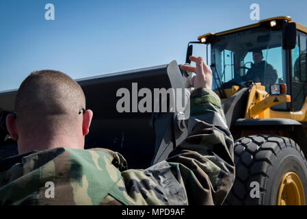 Aviateurs, avec le 374e Escadron de génie civil conducteur de matériel guides lors d'un terrain d'exercice rapide la réparation des dommages 8 février 2017, à Yokota Air Base, le Japon. RADR est un aérodrome moderne de processus de réparation afin de résoudre efficacement une piste en cas d'incident. (U.S. Air Force photo par un membre de la 1re classe Donald Hudson) Banque D'Images