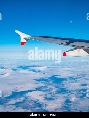 British Airways Airbus 319 aile d'avion vu d'avion en vol au-dessus de la fenêtre Banque du nuage blanc avec ciel bleu clair et la lune visible dans ciel en UK Banque D'Images