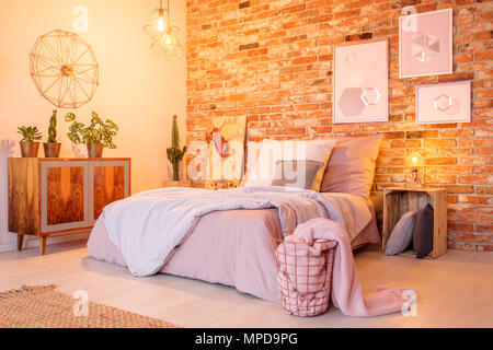 Chambre chaleureuse avec mur de brique, d'un lit double et une commode en bois Banque D'Images