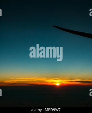 Coucher du soleil orange avec ciel bleu clair et un faible horizon, prises à partir de la fenêtre de l'avion, à l'extrémité de l'aile d'avion silhouette, décoller de Heathro, London, UK Banque D'Images