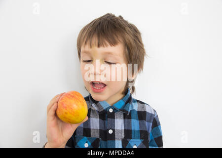 Portrait de cinq ans en chemise à carreaux bleu holding apple and smiling on white background Banque D'Images