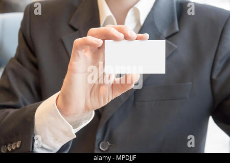 L'homme en costume sitting at table showing blank white carte immersive Banque D'Images
