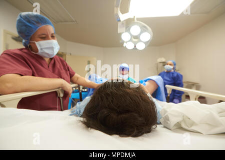 Patient en salle d'opération lumineux. L'équipe médicale travaillant sur la chirurgie Banque D'Images