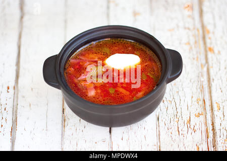 Le bortsch rouge. L'assiette traditionnelle ukrainienne. Dans une petite casserole. Sur le tableau blanc Banque D'Images