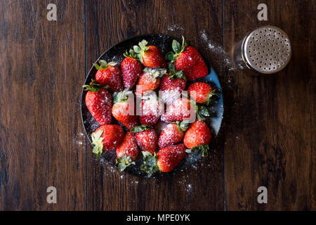 Produits frais bio fraise mûre avec du sucre en poudre sur la plaque noire. L'alimentation biologique. Banque D'Images