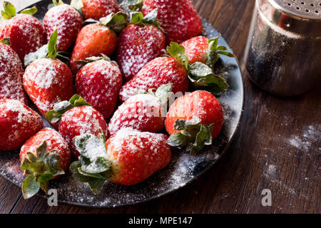 Produits frais bio fraise mûre avec du sucre en poudre sur la plaque noire. L'alimentation biologique. Banque D'Images