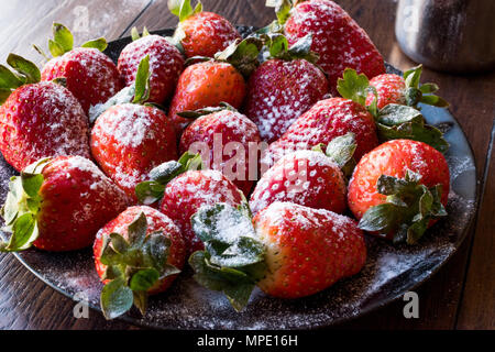 Produits frais bio fraise mûre avec du sucre en poudre sur la plaque noire. L'alimentation biologique. Banque D'Images