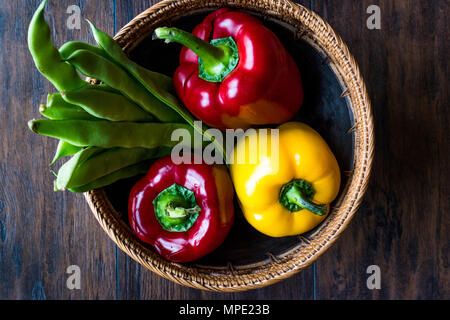 Poivron rouge et jaune avec des haricots verts dans le panier en bois. L'alimentation biologique. Banque D'Images