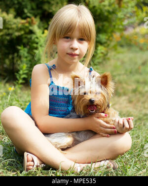 Fille 6 ans assis sur l'herbe avec un Yorkshire Terrier Banque D'Images