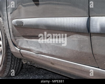 Close up detail d'une empreinte de la porte du conducteur à d'un accident de voiture ou d'accident d'automobile. Tordu et déformé en métal avec gros impact et peinture corps rayé Banque D'Images